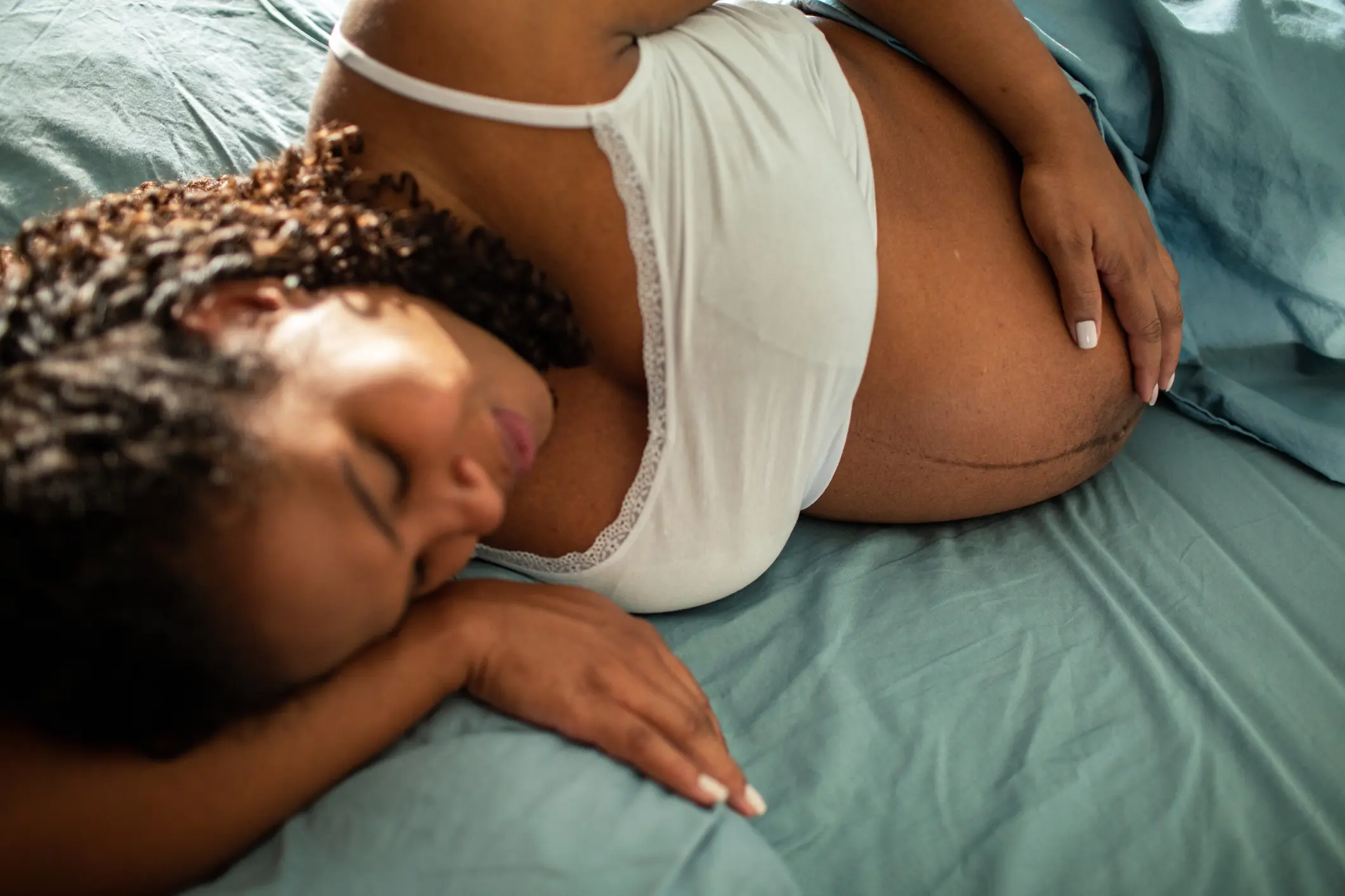 Relaxing pregnant woman on blue sheets